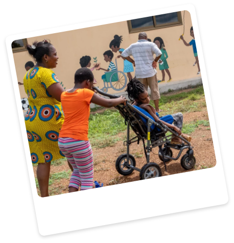 Carer pushing a child sat in medical pushchair.